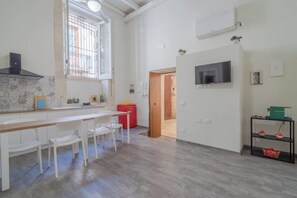 Une cuisine moderne avec un plan de travail en bois, des chaises blanches et une fenêtre à barreaux.