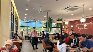 A restaurant with indoor seating, a waiter, and a wall with a motivational quote. - Hotel Marudu Inn (Kota Marudu)