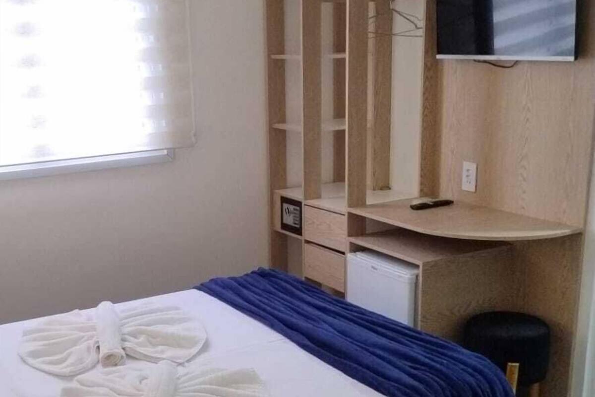 Une chambre d’hôtel avec un lit, une télévision, une armoire et un bureau.