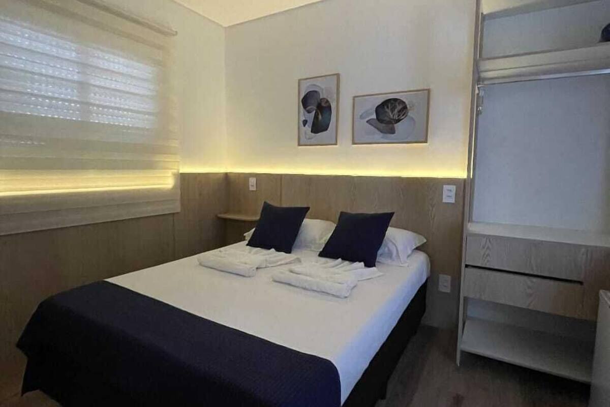 Une chambre d’hôtel comprenant un lit, une armoire et deux œuvres d’art accrochées au mur.