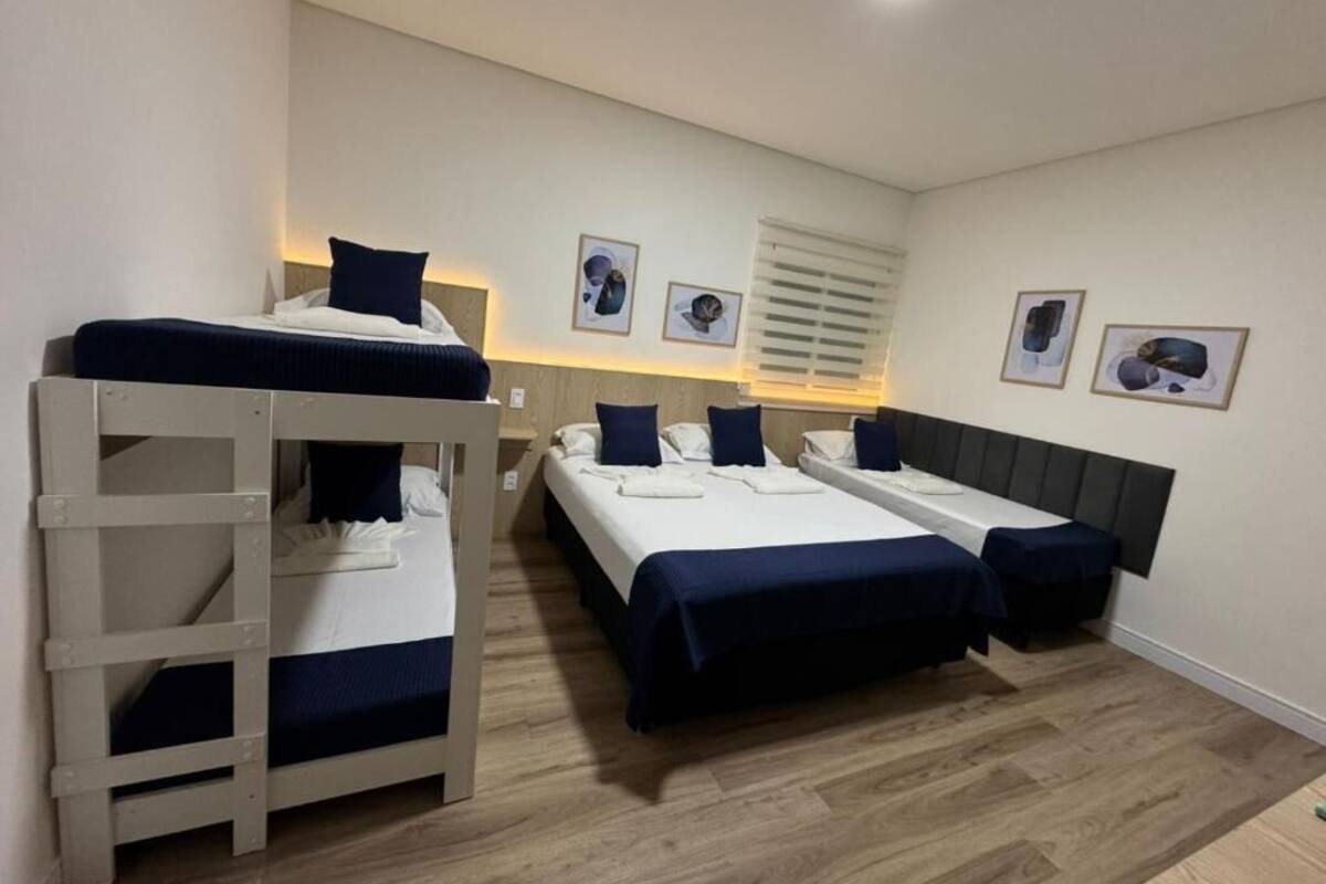 Une chambre avec des lits superposés, un bureau et une fenêtre avec des stores.