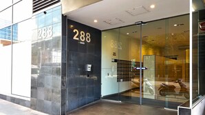 A modern building with a glass facade, the number 288 prominently displayed, and a visible elevator. - Skyline Studio Views on Spencer (Melbourne)