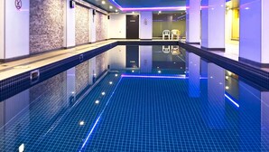 A modern indoor swimming pool with a blue tiled floor and a glass wall on one side. - Skyline Studio Views on Spencer (Melbourne)