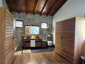 Relax in this serene bathroom with a bathtub, wooden vanity, and stone sinks.
