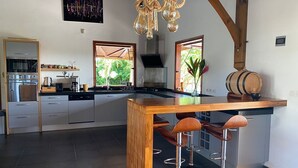 A modern kitchen with a central island, bar stools, and a wooden ceiling. - 3bed villa, pool, spa and sauna (Lamentin)