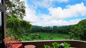 A balcony with a red wrought iron chair and table, surrounded by lush greenery and a mountainous landscape. - El Santuario Estate (Los Naranjos)
