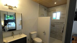 A modern bathroom with a large mirror, a sink, a toilet, and a shower area. - El Santuario Estate (Los Naranjos)