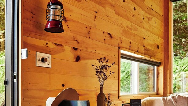 A wooden interior with a table, chair, and a hanging lantern. - Postcard Cabins Talladega Valley, Outdoor Collection by Marriott Bonvoy (Childersburg)