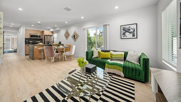 A modern living room with a green sofa, a round glass coffee table, and a striped rug. - Serene Escapes Hollywood  (Los Angeles)