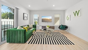 A modern living room with a green sofa, a round coffee table, and a black and white striped rug. - Serene Escapes Hollywood  (Los Angeles)