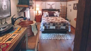 A cozy room with a wooden ceiling, a bed with a patterned bedspread, a wall-mounted TV, and a framed picture of a dog. - The "Eleanor Rigby" DIRECT STREAM FRONT W HOT TUB

 (Flag Pond)