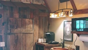 A rustic kitchen with wooden cabinets, a coffee maker, a microwave, and a framed picture on the wall. - The "Eleanor Rigby" DIRECT STREAM FRONT W HOT TUB

 (Flag Pond)
