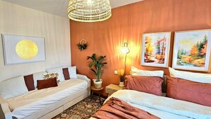 A hotel room with two beds, a large circular artwork, a wall-mounted lamp, and two framed paintings. - A change of scenery (Poitiers)