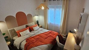 A bedroom with a bed, bedside table, lamp, and a window with curtains. - A change of scenery (Poitiers)