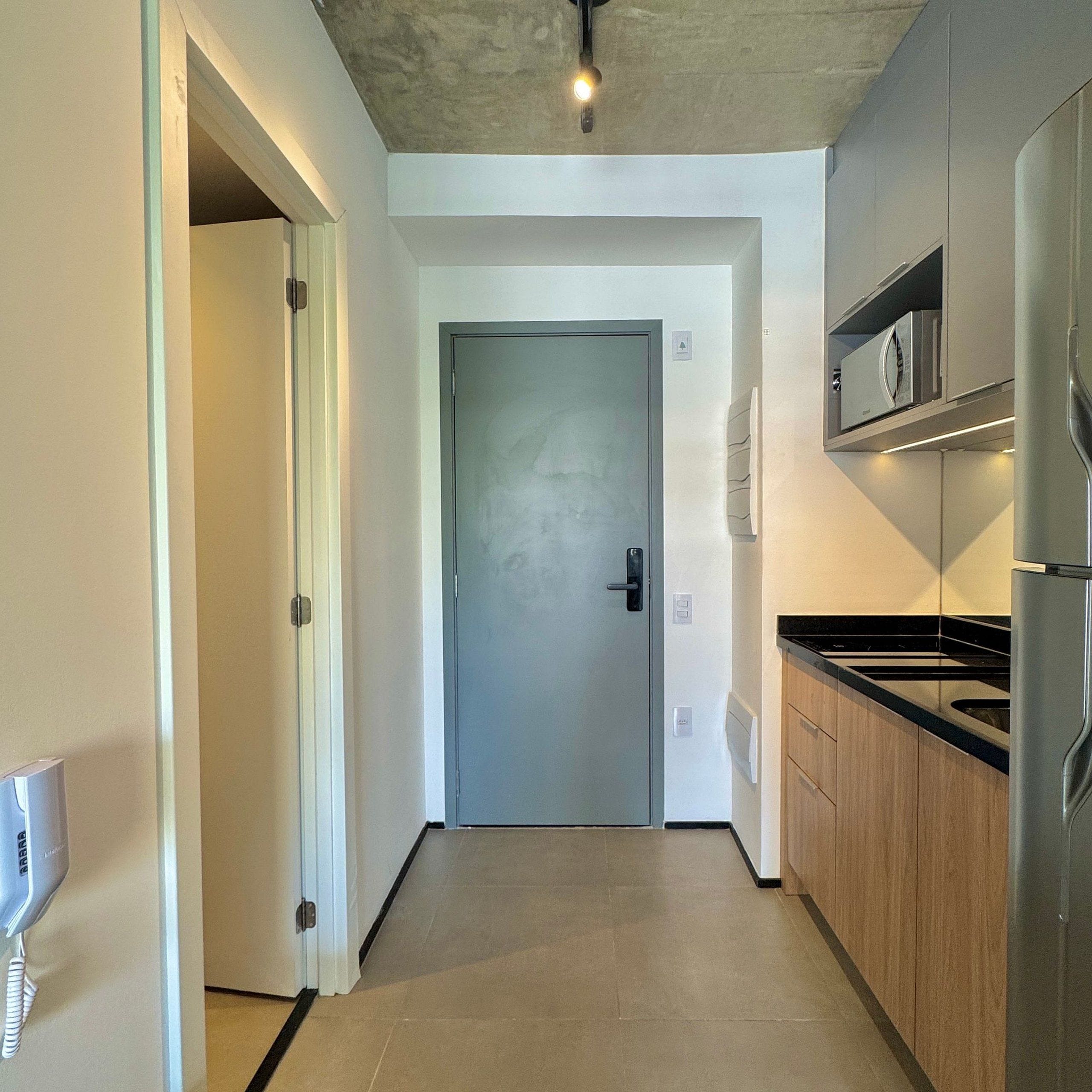 A modern kitchen with stainless steel appliances, a wooden cabinet, and a tiled floor.