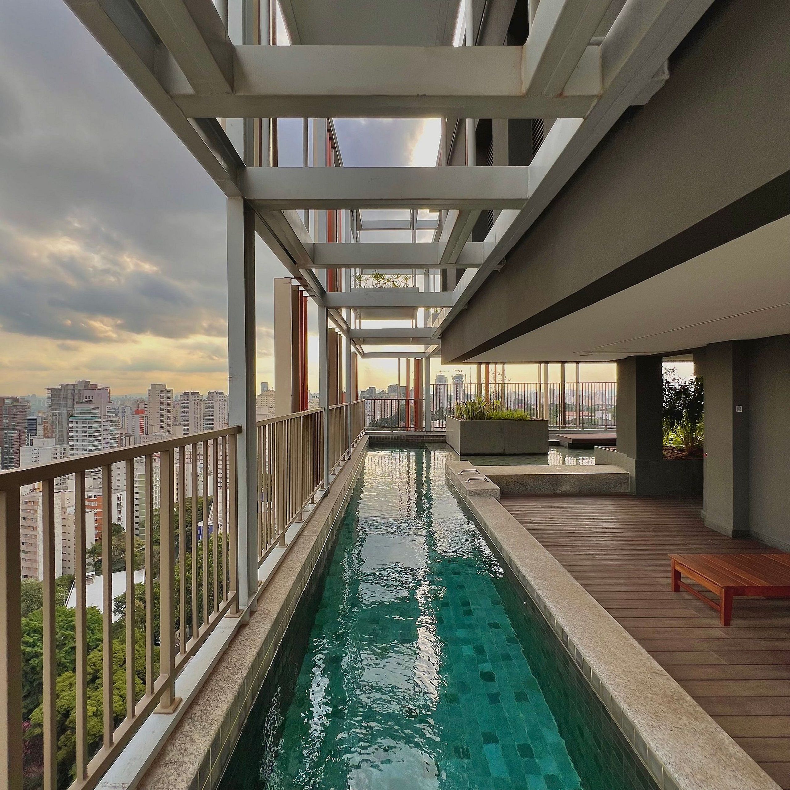 A rooftop pool with a city view, a wooden deck, and a modern architectural design.