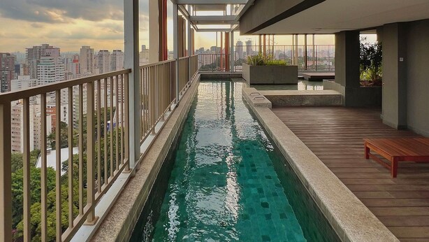 A rooftop pool with a city view, a wooden deck, and a modern architectural design. - ON MELO ALVES (São Paulo)