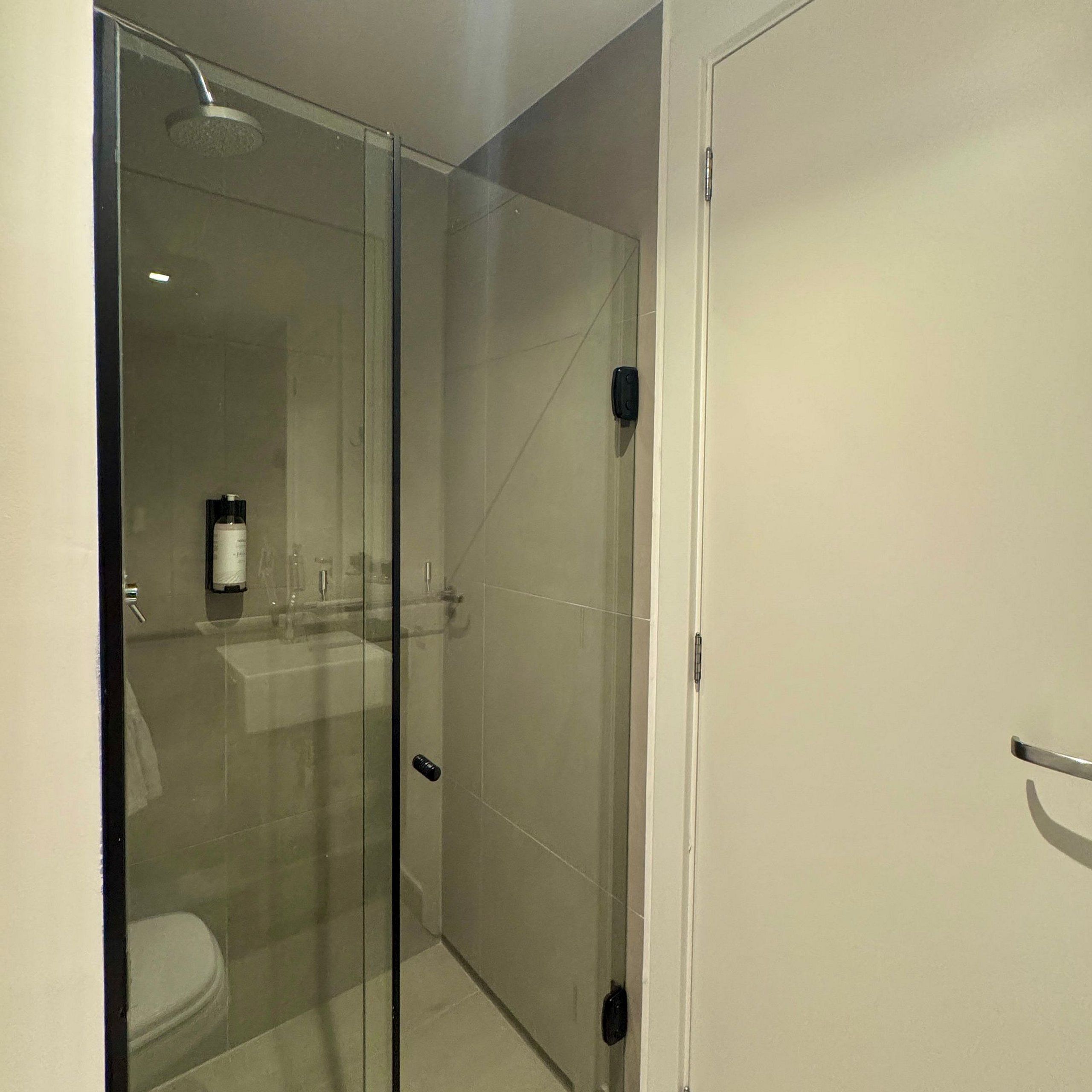 Uma casa de banho moderna com cabine de duche em vidro, sanita e lavatório com espelho.