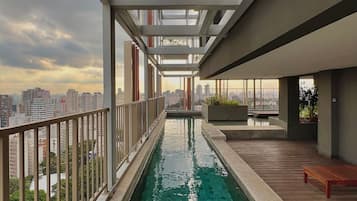 Piscina no terraço com vista para a cidade, deck de madeira e design arquitetônico moderno.