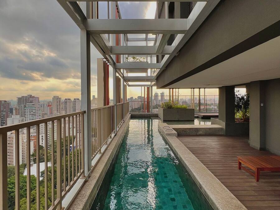 A rooftop pool with a city view, a wooden deck, and a modern architectural design.