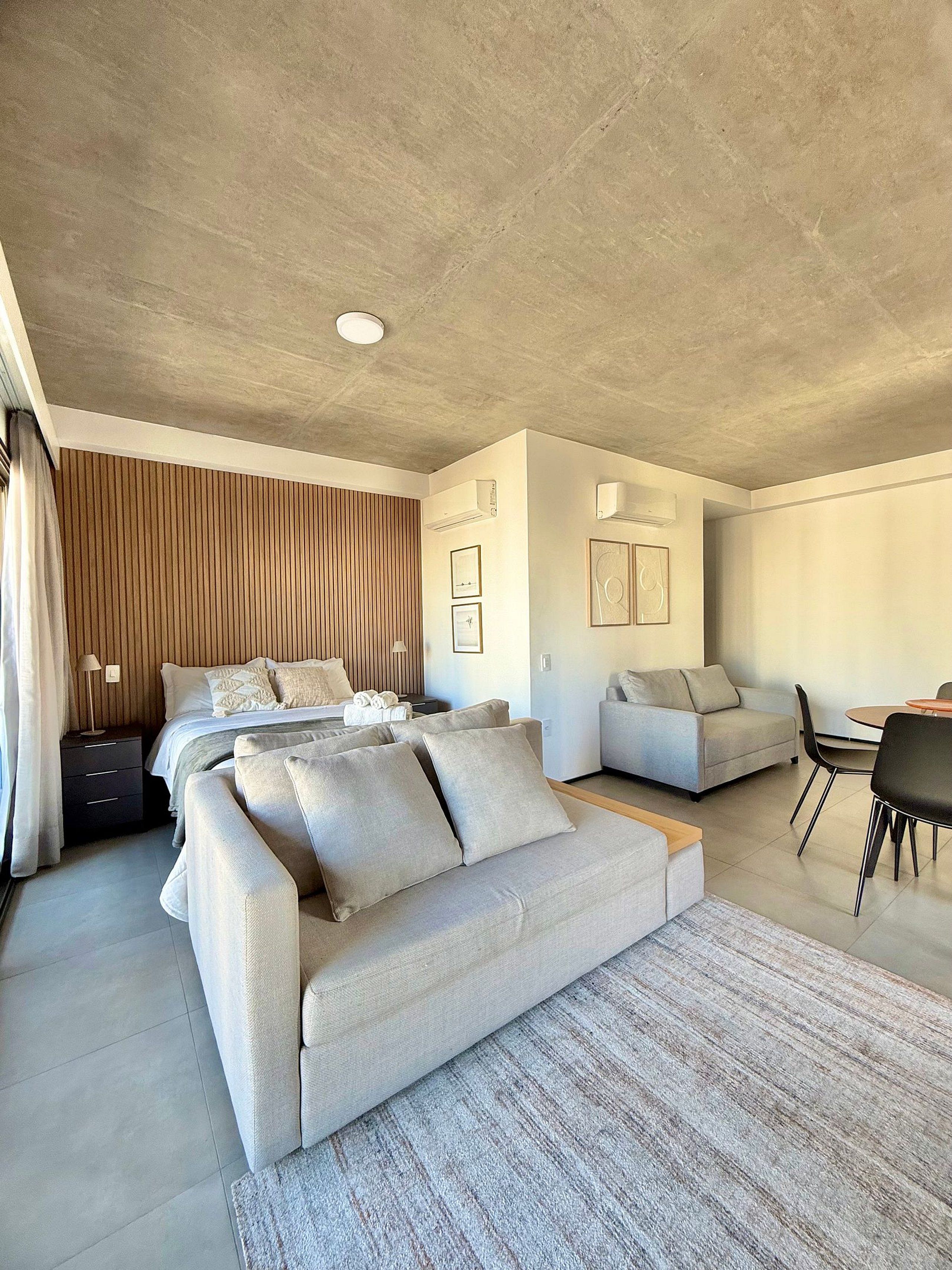 Un dormitorio moderno con una cama grande, un sofá, un escritorio y un comedor.