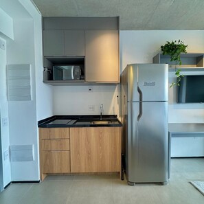 A modern kitchen with a stainless steel refrigerator, wooden cabinets, a microwave, and a sink. - ON MELO ALVES (São Paulo)