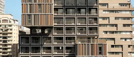 A high-rise building with multiple balconies, a modern architectural design, and a clear sky.