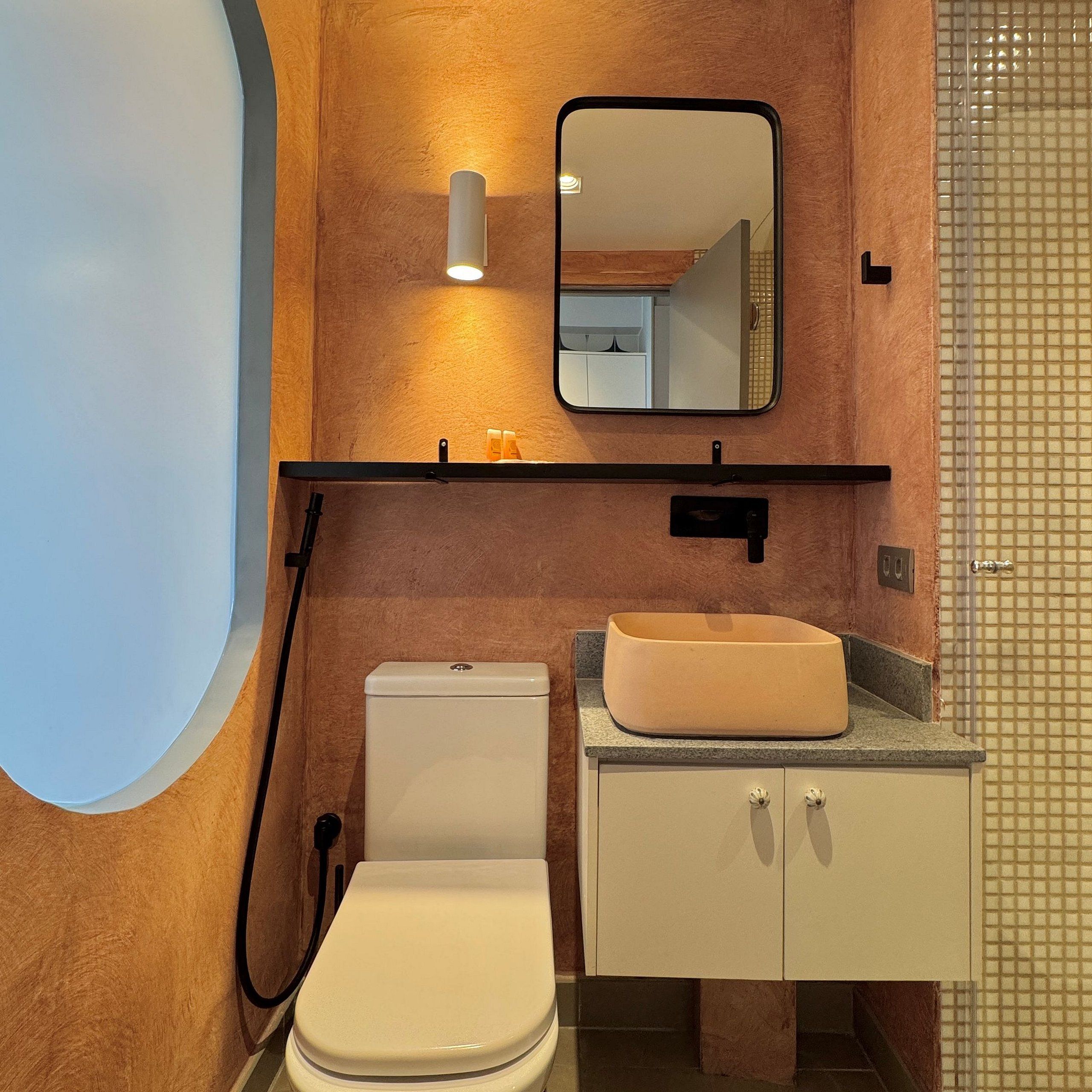 A bathroom with a toilet, sink, mirror, and bathtub.