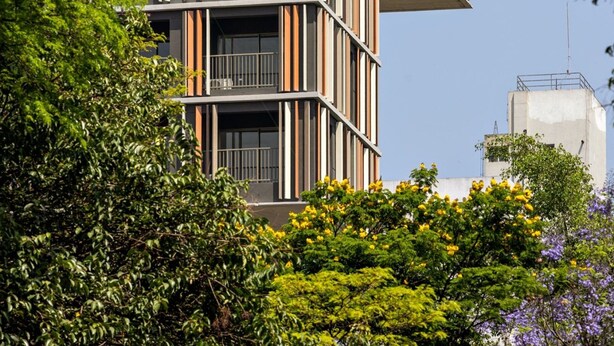 Un edificio moderno con un diseño arquitectónico único, que presenta varios balcones y una combinación de líneas verticales y horizontales.