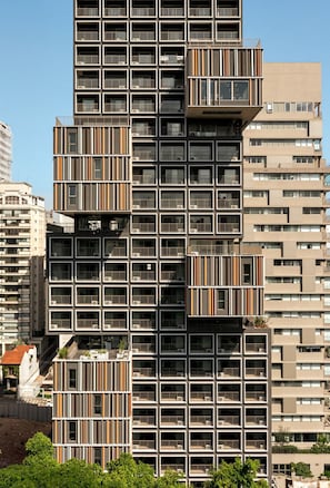 A high-rise building with multiple balconies, a modern architectural design, and a clear sky. - ON MELO ALVES (São Paulo)