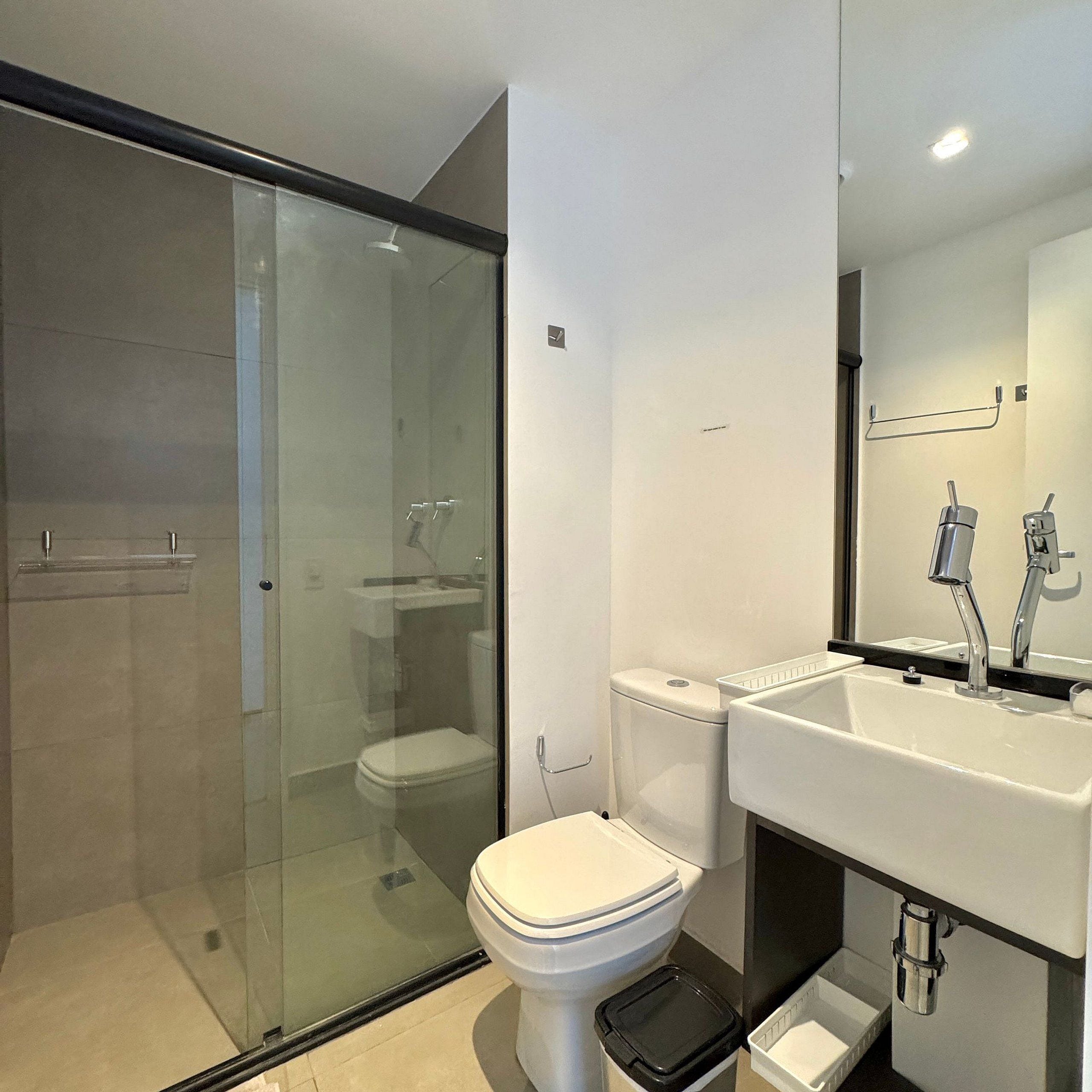 A modern bathroom with a glass shower enclosure, a white toilet, and a sink with a mirror.