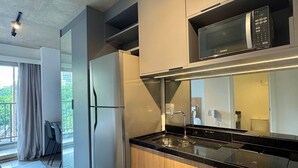 Una cocina moderna con un refrigerador de acero inoxidable, un microondas y gabinetes de madera.