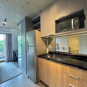 Una cocina moderna con un refrigerador de acero inoxidable, un microondas y gabinetes de madera.