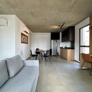 A modern living space with a sofa, dining table, chairs, a kitchen area, and a large window. - ON MELO ALVES (São Paulo)