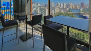 A modern office space with a large table and chairs, large windows with a city view, and a geometric patterned wall. - ON MELO ALVES (São Paulo)