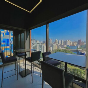 A modern office space with a large table and chairs, large windows with a city view, and a geometric patterned wall. - ON MELO ALVES (São Paulo)