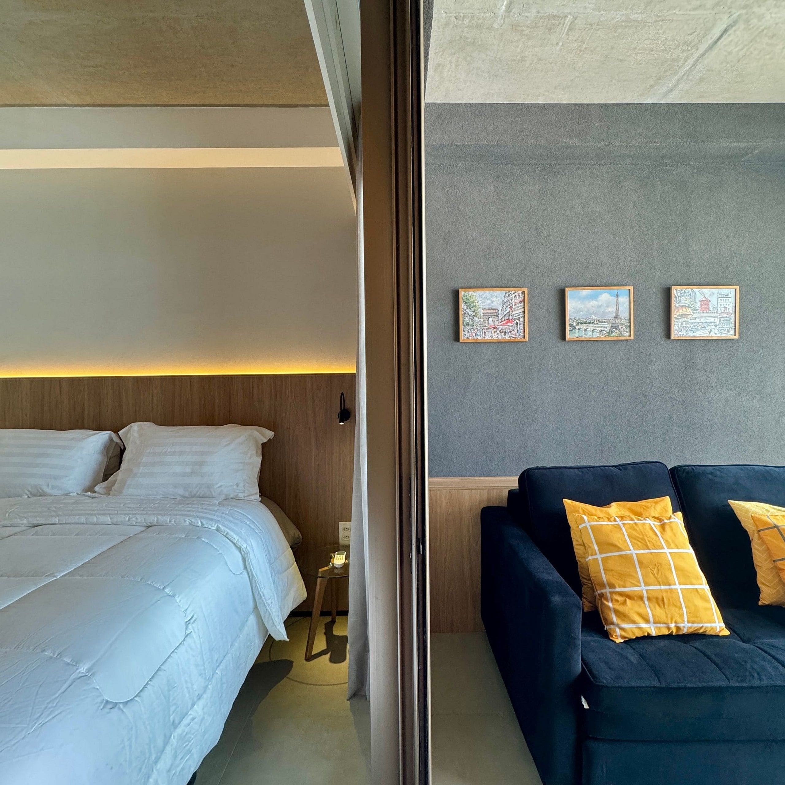 Una habitación de hotel con una cama, un sofá y tres cuadros en la pared.