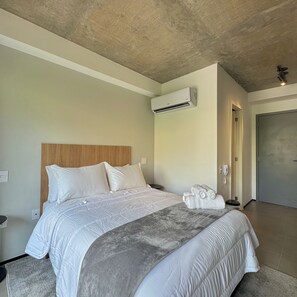 A hotel room with a bed, an air conditioning unit, a telephone, and a door. - ON MELO ALVES (São Paulo)