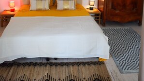 Une chambre à coucher avec un grand lit, deux lampes de chevet, une armoire en bois, un miroir et un luminaire suspendu.