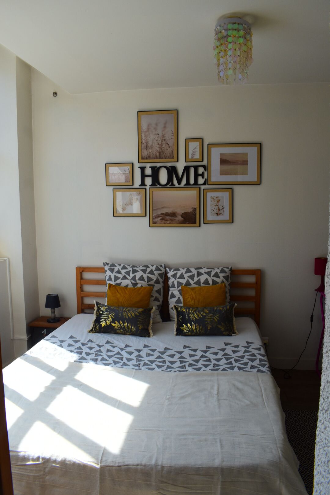 Ein Schlafzimmer mit einem Bett, einem Nachttisch, einer Wandlampe und einer Deckenleuchte.