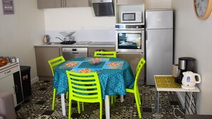 Une cuisine compacte comprenant une table à manger, des chaises, un four à micro-ondes, un réfrigérateur et une machine à café.