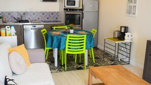 Un espace de vie compact comprenant un coin cuisine, un coin repas avec une table et des chaises, un canapé et une table basse.