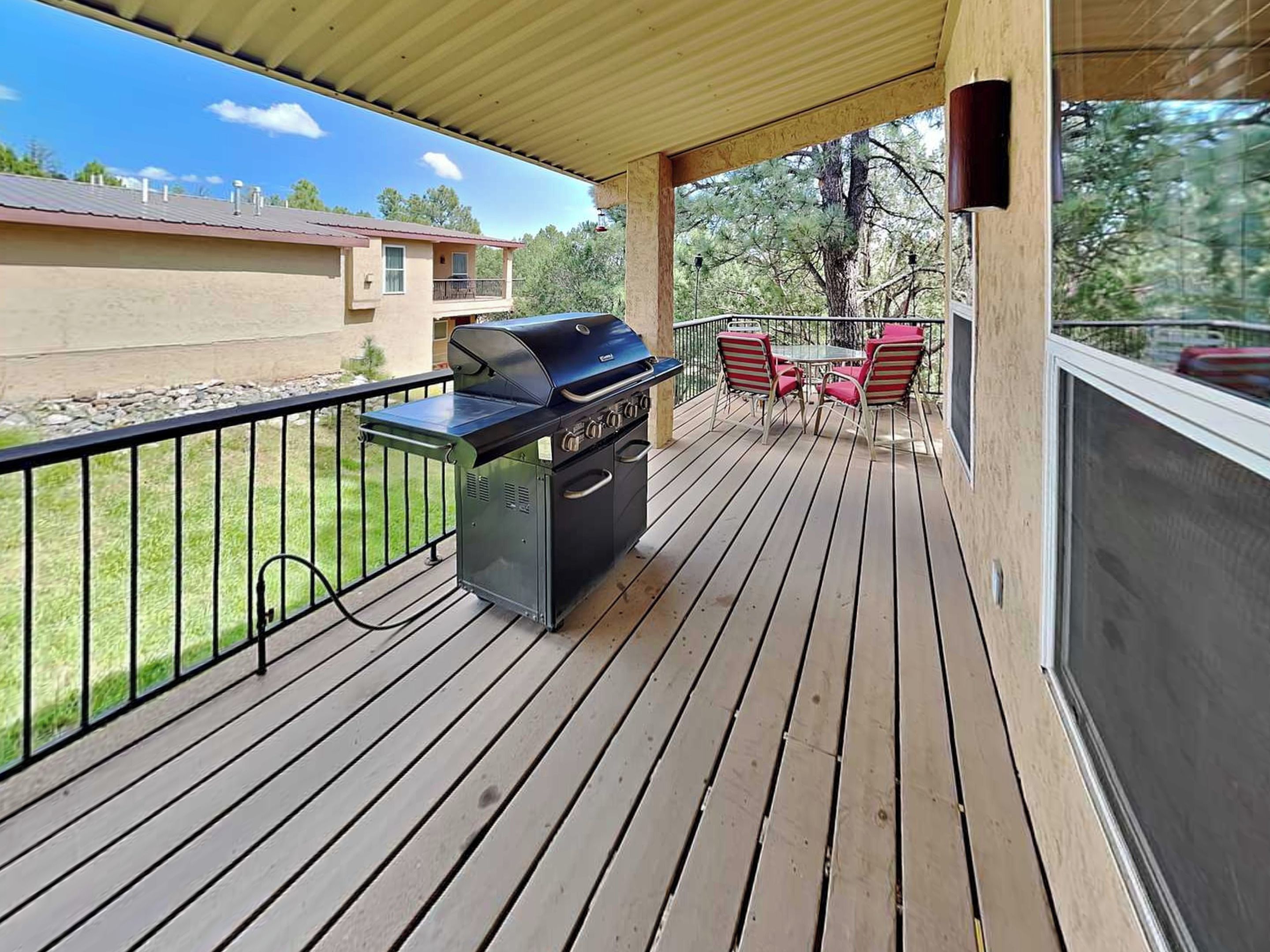 A covered outdoor deck with a barbecue grill and seating area.
