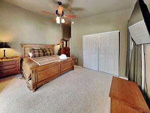 A bedroom with a wooden bed, a ceiling fan, a dresser, and a wardrobe. - Alto Paradise by Ruidoso Vacation Rentals (Alto)