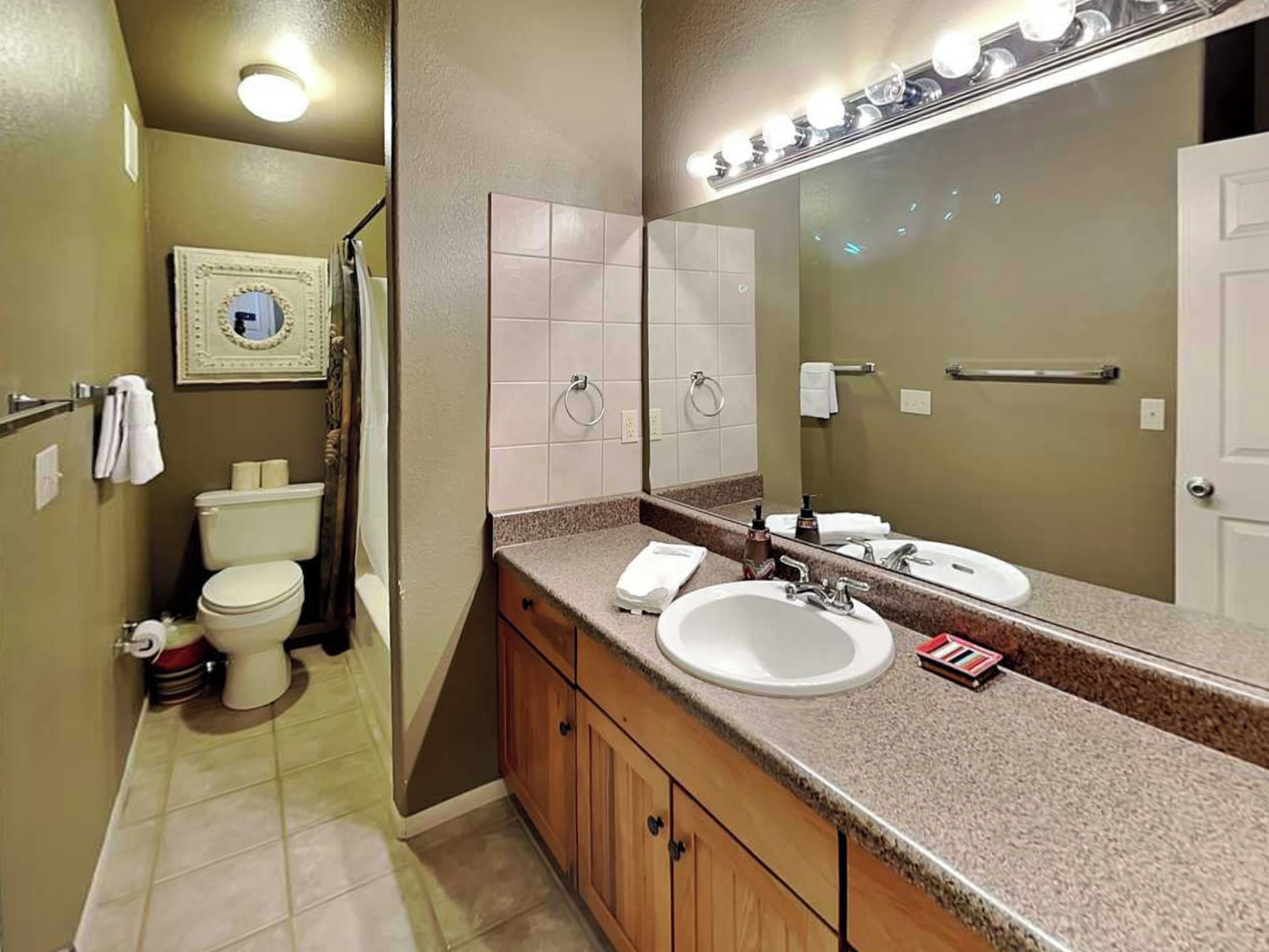 A bathroom with a toilet, sink, and mirror.