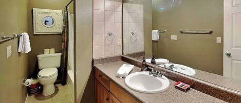 A bathroom with a toilet, sink, and mirror.