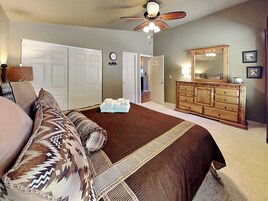 Un dormitorio con cama, cómoda, espejo y ventilador de techo.