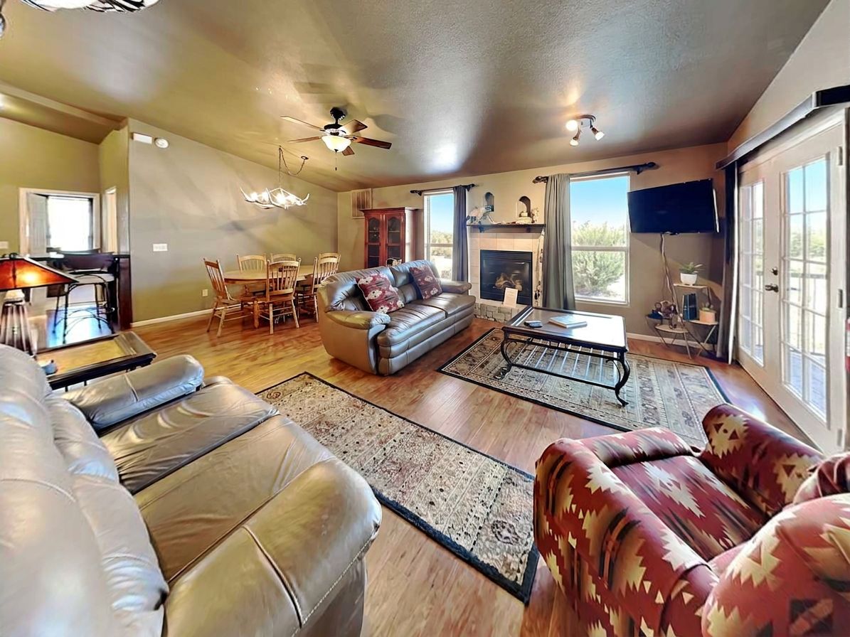 A spacious living room with a fireplace, leather sofas, and a dining area with a table and chairs.