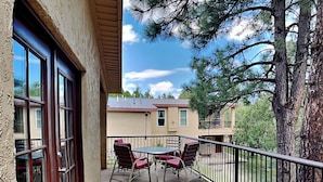 A wooden deck with a table and chairs, a railing, and a view of houses and trees. - Alto Paradise by Ruidoso Vacation Rentals (Alto)