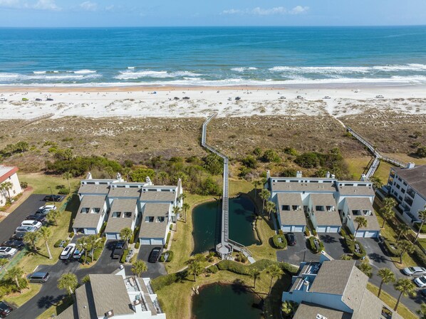 A coastal residential area with beachfront properties, a connecting bridge, and a parking lot. - Sea Winds 52 by Distinctive Beach Rentals (St. Augustine)